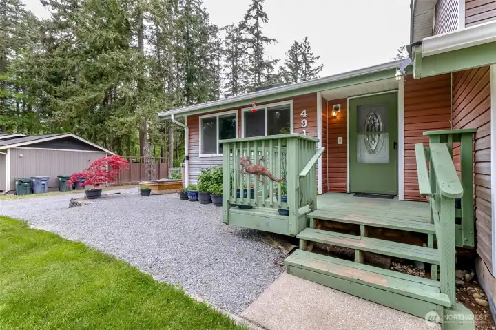 Front porch, low maintenance vinyl siding and gravel walkway to additional parking to the left of the house.