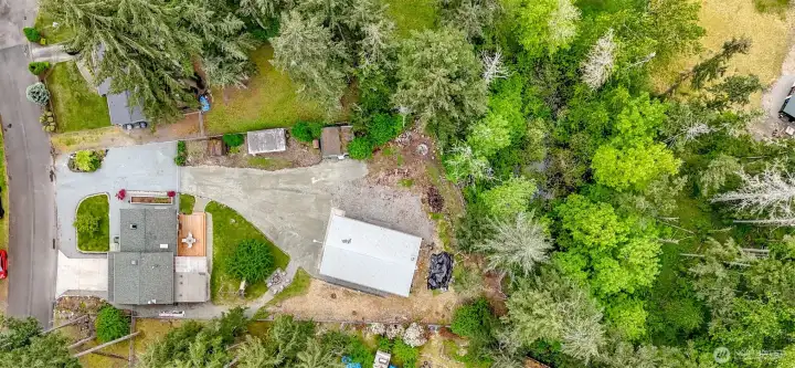 This aerial photo betters shows the two outbuildings, chicken coop and shop in relation to the house as well as some of the property that extends beyond the shop to the back of the undeveloped property.