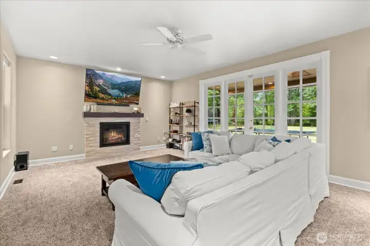Cozy family room with updated stone-accented fireplace and French door access