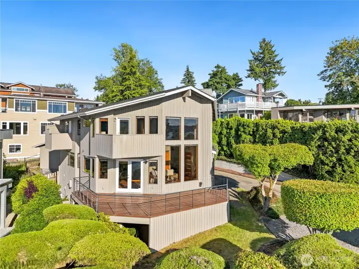 Stunning custom home nestled among lush landscaping with dramatic architectural lines and Lake Washington views beyond