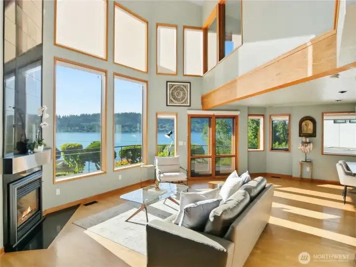 Light-filled main living area with soaring ceilings, walls of glass, and stunning lake views as the centerpiece
