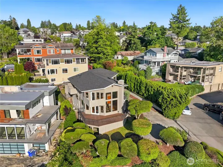 Perched above the road on its own elevated footprint, the home's striking deck and rooflines stand out amid mature trees and greenery