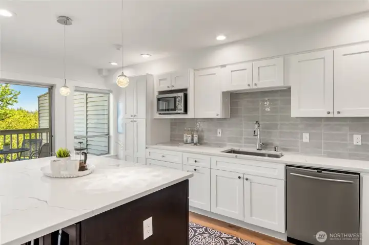 Custom kitchen with shaker cabinets, quartz counters, and tile backsplash.