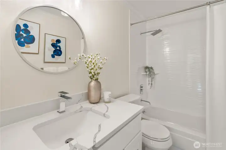 Upper hall full bath with tiled shower surround, updated vanity, quartz counters and specialy lighting.