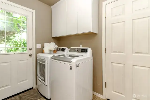 Utility room with upper cabinets, door leading to back of the house and the door to the right leads to the 3 car garage.