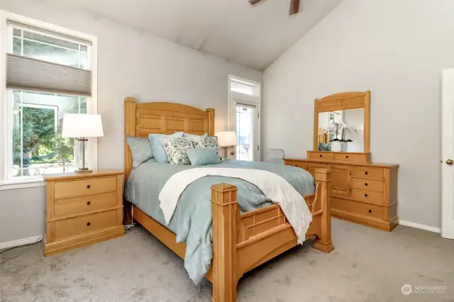 Primary bedroom has vaulted ceilings, ceiling fan and door that leads to the hot tub and composite deck.