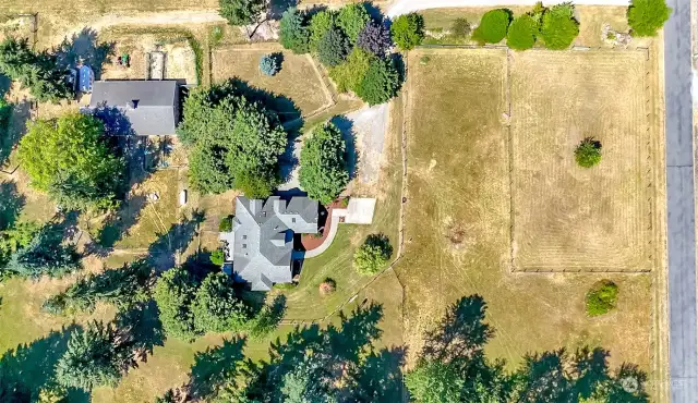 Awesome aerial view of the arena at the East side next to the road, pasture to the West of the arena, house, dog run, barn to the far West and additional pasture and driveway.