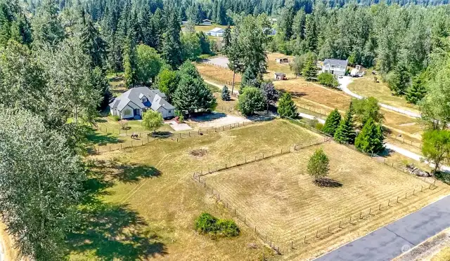 Sand footed arena with tree in the center. The barn is nestled back behind the grove of trees to the right of the house. Full 5 acres with access to the bridle trail.