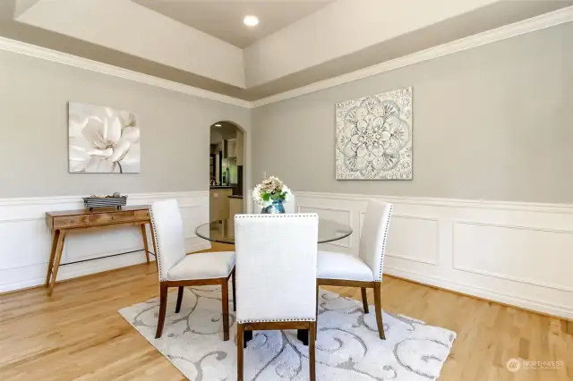 This view of the formal dining room shows the wainscoting on the walls as well as the entry to the kitchen and great room.