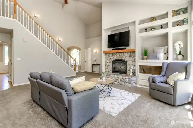 This angle of the great room shows the river rock fireplace, storage and decor built ins and stairway to extra bedrooms.