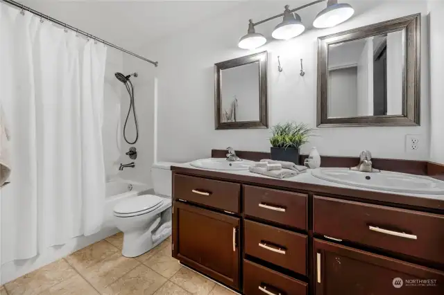 Secondary bathroom upstairs offers double sink vanity and tub/shower combo.