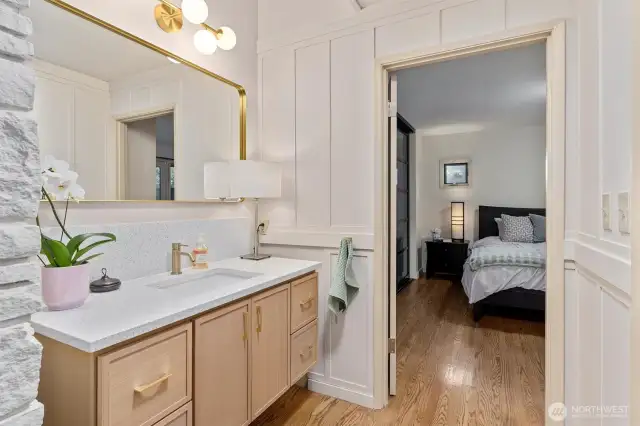 Sleek primary bath features light oak vanity, quartz counters & brushed gold accents.