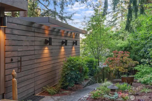 Sleek horizontal privacy wall with integrated lighting guides through Japanese-inspired garden.