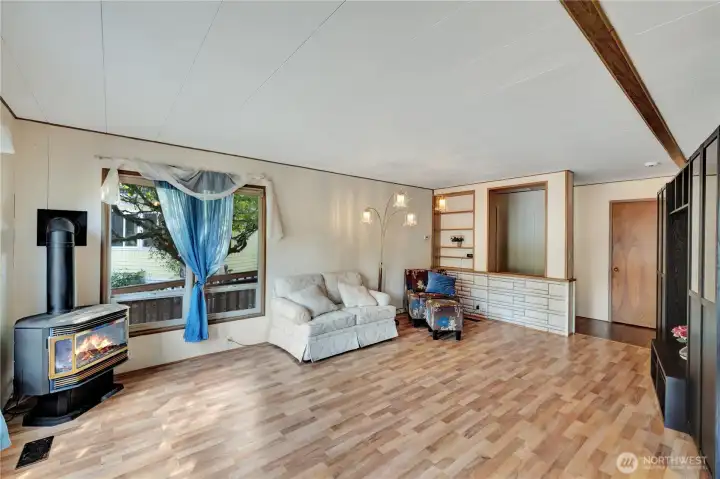 The cheerful living room features beautiful flooring & a free-standing gas stove.
