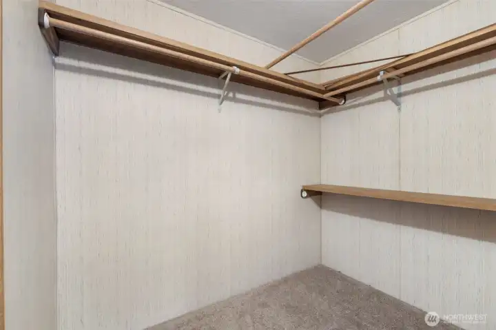Primary walk-in closet with built-in shelving and hanging space for organized storage.
