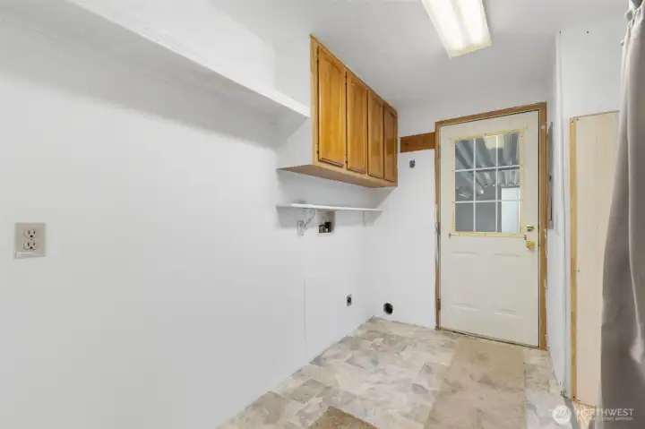 Laundry room with upper storage cabinets and convenient exterior access.