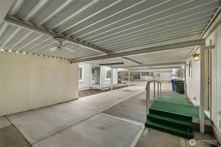 Large covered carport with protected parking and attached shop/storage area.