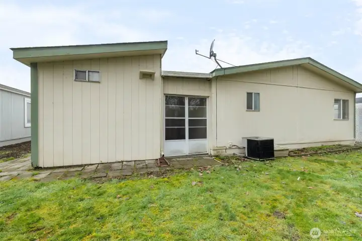 Back of home with convenient access to shop/storage area, backyard, and efficient heat pump system.