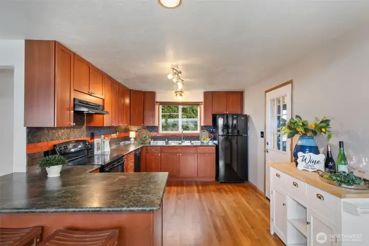Updated kitchen with oak floors and leathered granite slab counter tops. Utility room/laundry room to the right.
