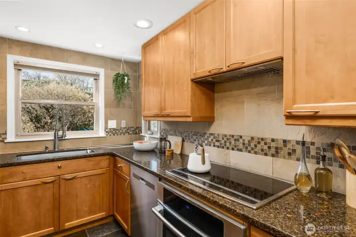 The kitchen features updated stainless steel appliances, a new kitchen hood vent, wood cabinetry and slate flooring.