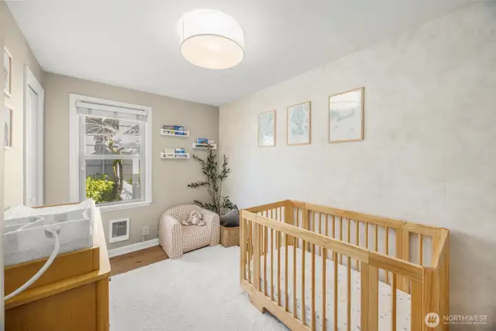 Secondary Bedroom on the main floor features ample natural light, hardwood floors and updated wallpaper.