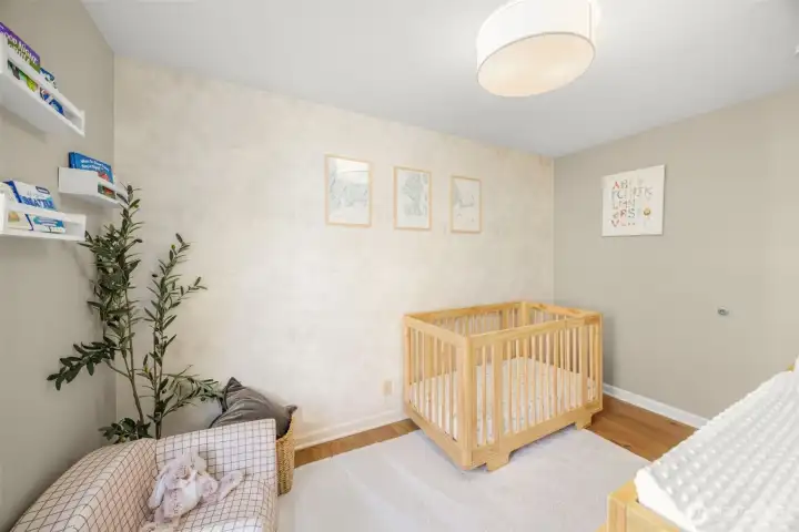 Secondary Bedroom on the main floor features ample natural light, hardwood floors and updated wallpaper.