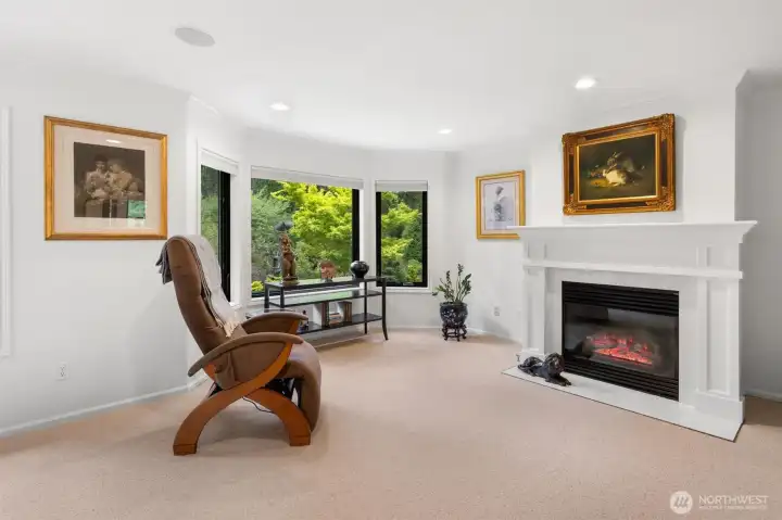 Seating area in primary bedroom with gas fireplace and private garden views.
