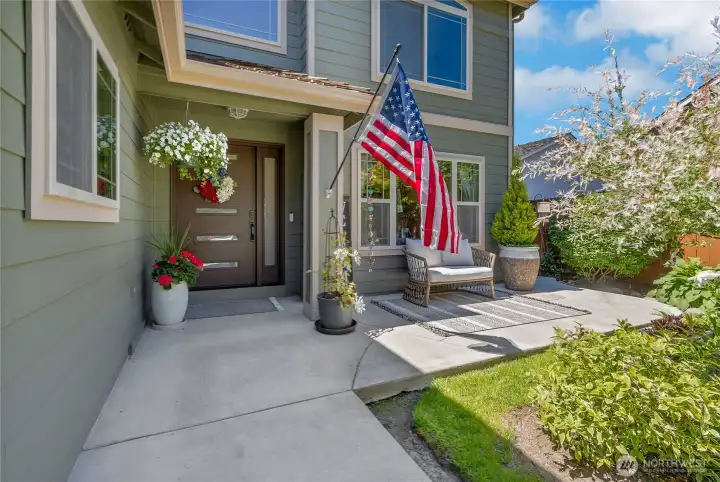 A thoughtfully expanded front porch creates a welcoming outdoor space perfect for morning coffee, visiting with neighbors, or simply enjoying the beautifully landscaped setting.