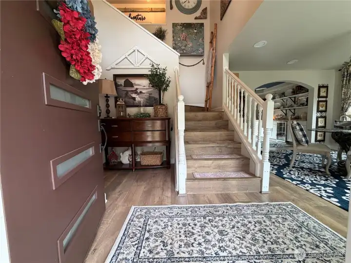 Welcome home to a bright and inviting foyer where warm finishes, an open staircase, and seamless sightlines create an immediate sense of comfort and connection.