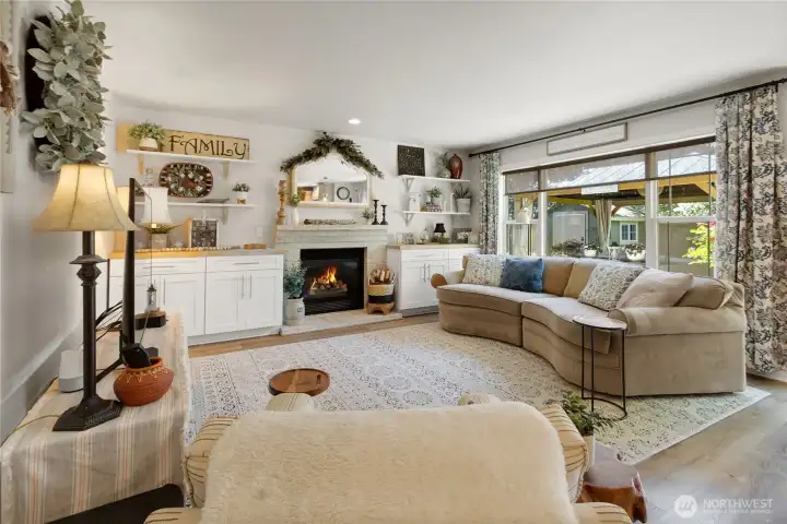 Designed for gathering, this inviting living room features custom built-ins, a cozy gas fireplace, and a stunning picture window that frames the backyard retreat beyond.
