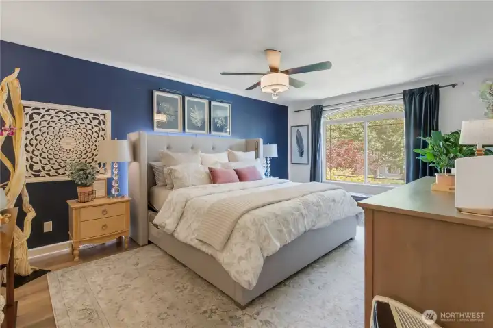 Wake up to natural light and peaceful views through the dramatic curved window, creating a bright and inviting primary retreat designed for comfort and relaxation.