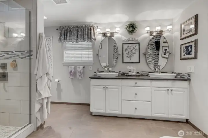 Designed with comfort in mind, the beautifully updated primary bath features dual vanities, heated tile floors, a spacious tiled shower, and thoughtful finishes that create a true spa-like experience.