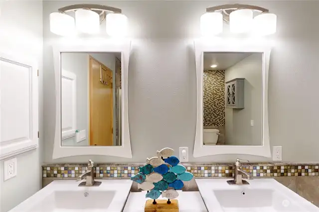 Two vanity sinks and beautiful tile work in the primary bathroom - which has a heated  floor.