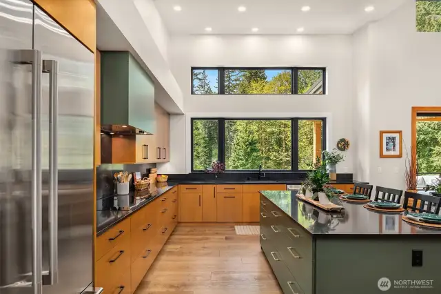 36"- 5 Zone Induction Cooktop with 36" hood and 600C FM blower. Large center island with two-tone accent earthy green cabinets, loaded with easy access drawer storage.