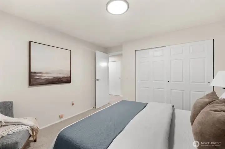 This secondary bedroom utilizes its expansive window to maximize the 'open-concept' feel of the home, supported by a walk-in closet designed for the modern lifestyle.