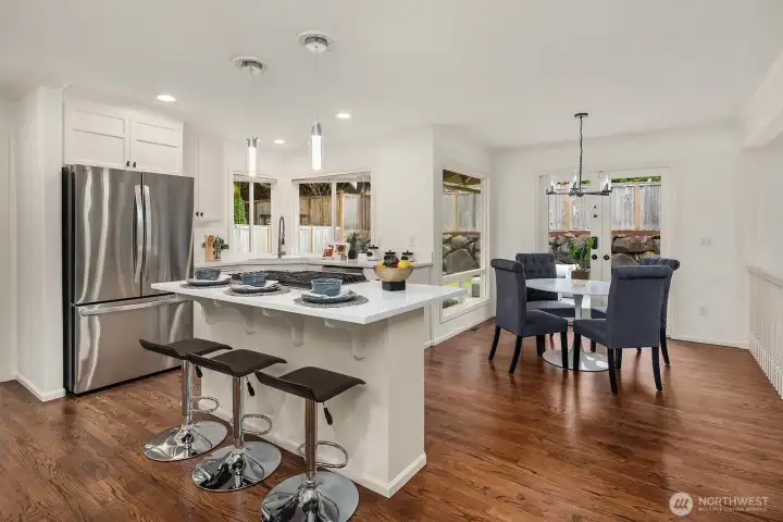 The beautifully appointed chef's kitchen features upgraded quartz counters, stainless steel appliances, a generous island with bar seating, and rich hardwood floors — designed for both everyday living and effortless entertaining.