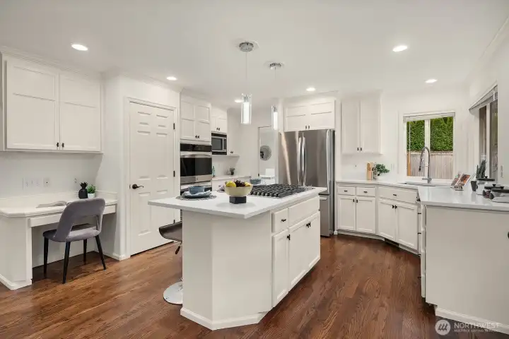 Beautifully designed with white shaker cabinetry, quartz countertops, a center island, and a built-in desk nook, this chef's kitchen delivers both style and functionality in every detail.