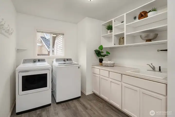 A well-appointed laundry room features full-size washer and dryer, built-in shelving, and ample cabinetry, offering practical storage and functionality tucked conveniently within the home.