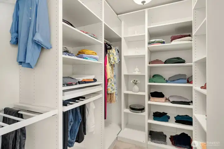 The expansive walk-in closet features custom built-ins with dedicated hanging, shelving, and storage sections, offering exceptional organization and a boutique-like experience every day.