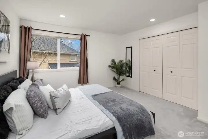 This generously sized upper level bedroom offers a large closet with double doors, plush carpet, and a bright window, providing comfort and functionality for family or guests.