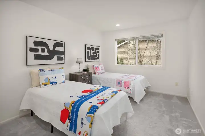 A spacious and cheerful upper level bedroom with dual windows flooding the room with natural light, offering plenty of room for two and endless possibilities for personalization.