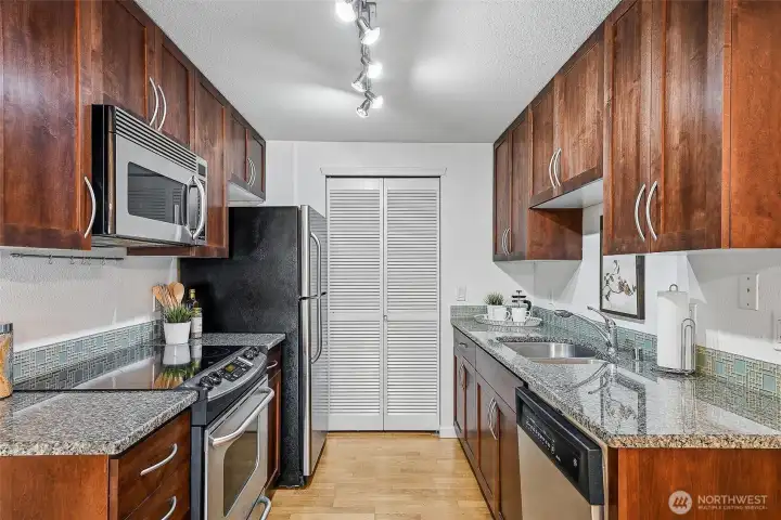 Slab granite counters and stainless steel appliances. Stackable washer and dryer discreetly located behind louvered doors