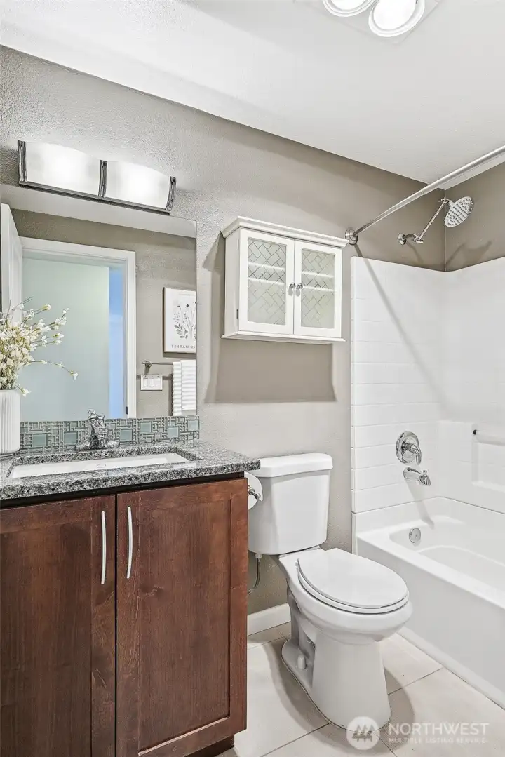 Full bath with granite counters, tile floor, and shower/tub combo