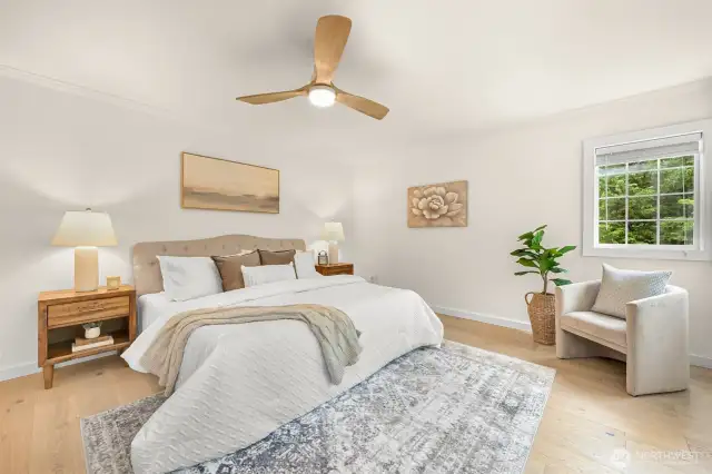 A large primary sweet with new light fixtures and flooring, along with views out to the greenbelt.