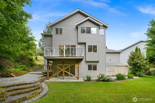 The back yard has the terraced area for a fire pit and chairs and space to kick a ball around. Owners used to have a sauna in front of the shed as well.