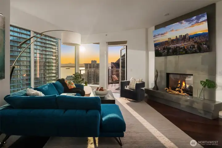 The open living space is filled with natural light and anchored by a dual-sided gas fireplace that seamlessly connects the living room and primary suite.