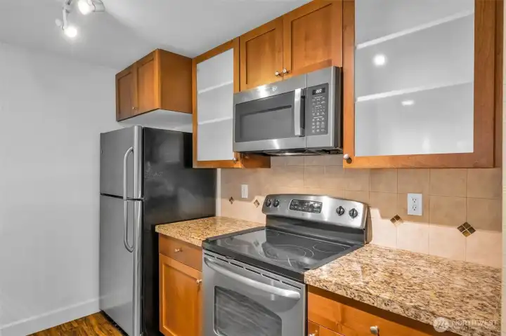 The kitchen has an amazing workspace. Enjoy shaker cabinets, new microwave, glass cooktop and tons of cabinet space. Granite counters and 1 compartment sink.  Tile accents make the space feel modern and clean up is a breeze.