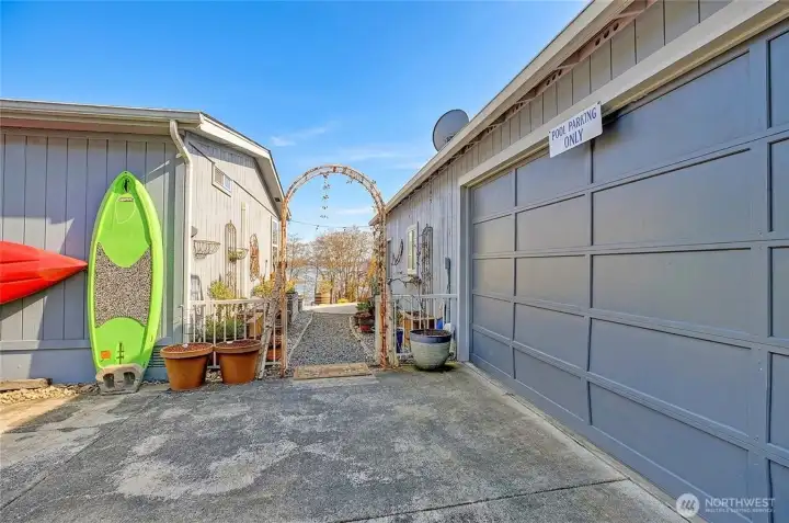 Charming walkway between home and garage/shop leading to outdoor spaces with glimpses of the water.