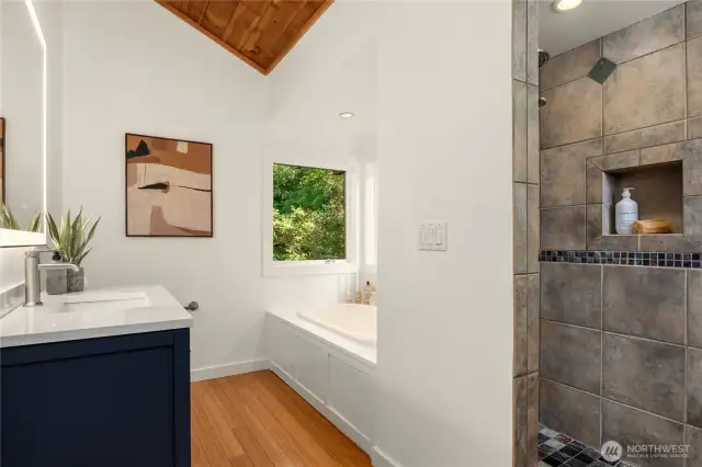 The primary's private bath features vaulted ceilings, a tiled walk-in shower and separate soaking bath.