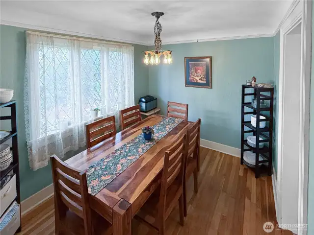 Gather in a dining room that radiates vintage charm, featuring original leaded glass windows that filter soft natural light through delicate lace curtains. The warm hardwood floors and classic chandelier create a perfect backdrop for holiday dinners or weeknight takeout alike. It’s a space that honors the home’s history while making everyday moments feel a little more special.